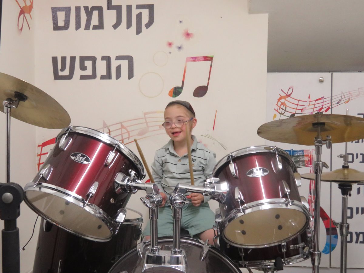 יוסף מתופף על מערכת התופים בחדר התרפיה במוזיקה בבית הספר