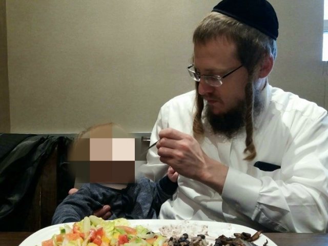 הרב דוד אוברלנדר ז"ל מאכיל את בנו הפעוט. צילום פרטי
