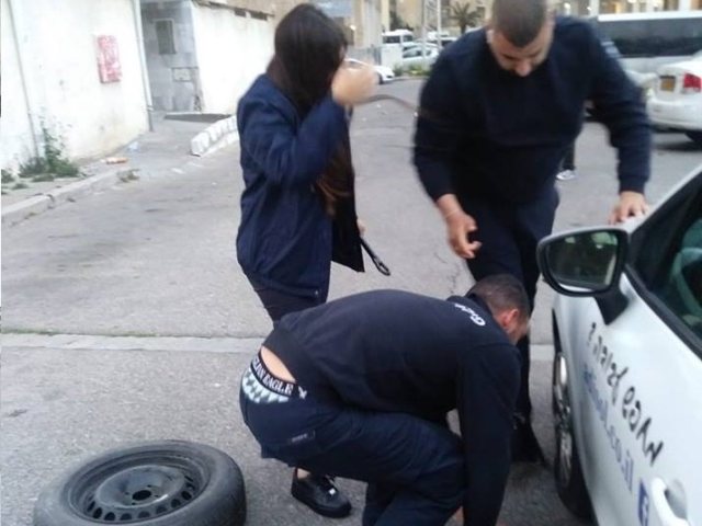 אנשי הפיקוח העירוני מסייעים לתושבת העיר להחליף את הגלגל
